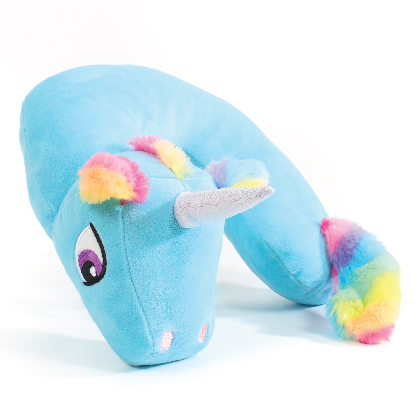 Side view of the Blue Unicorn Kids' Junior Travel Pillow. This travel neck pillow features a blue body with embroidered eyes and furry, rainbow-colored ears, hair, and tail, as well as a shimmery horn.