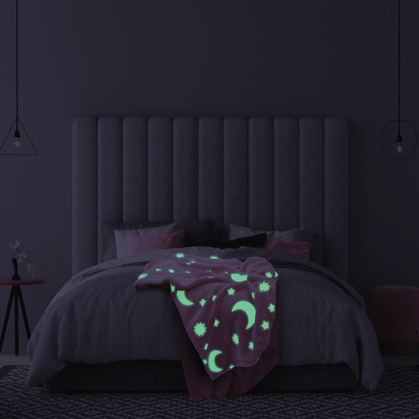The Glow in the Dark Throw Blanket in Pink Moon and Stars spread across a children's bed, glowing in the dark.