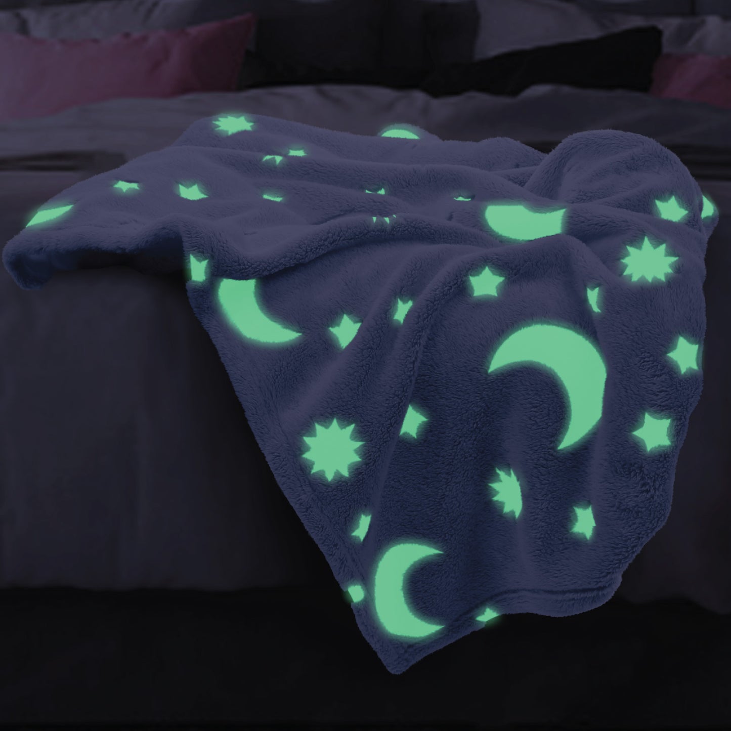 The Glow in the Dark Throw Blanket in Blue Moon and Stars spread across a children's bed, glowing in the dark.