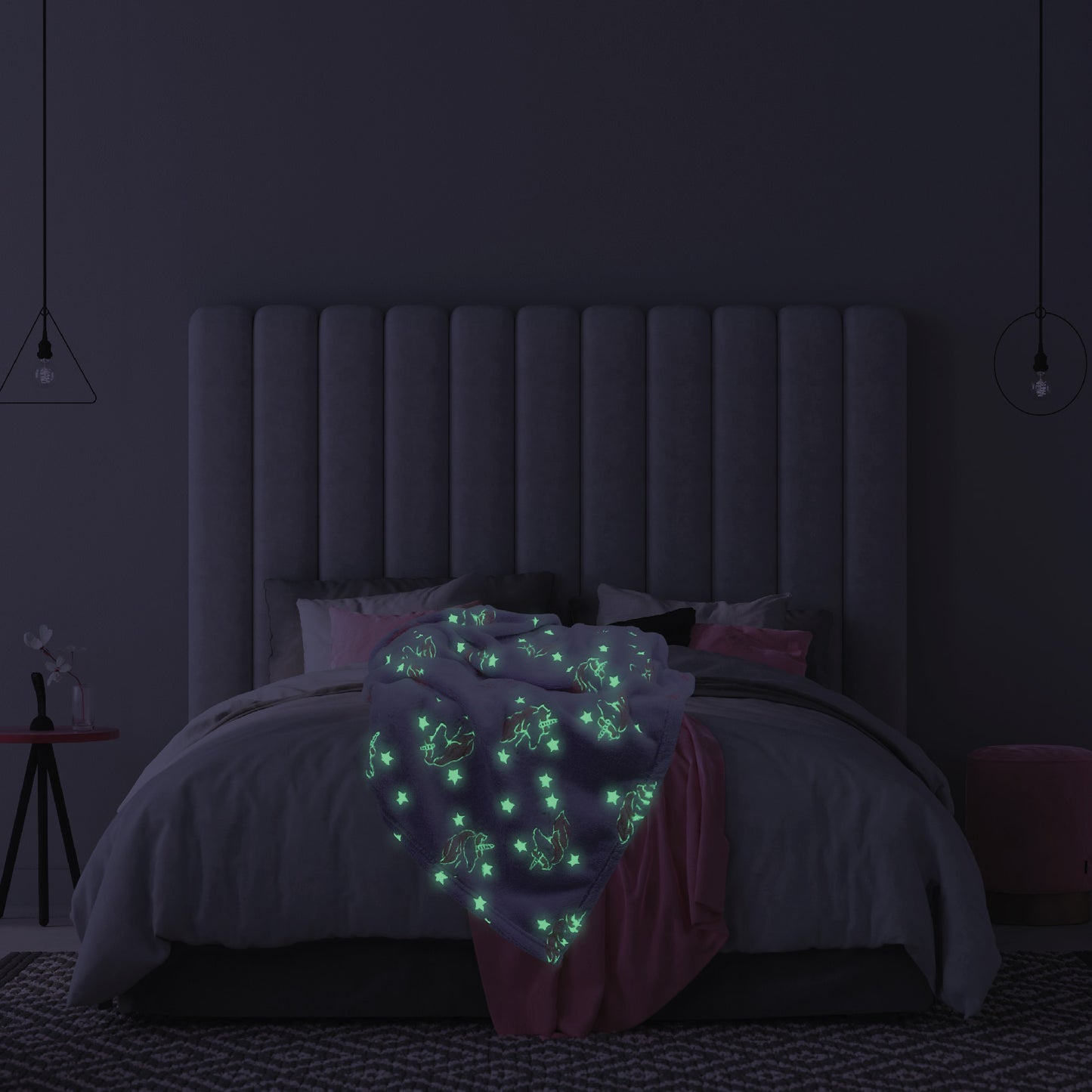 The Glow in the Dark Throw Blanket in Pink and Purple Unicorns spread across a children's bed, glowing in the dark.