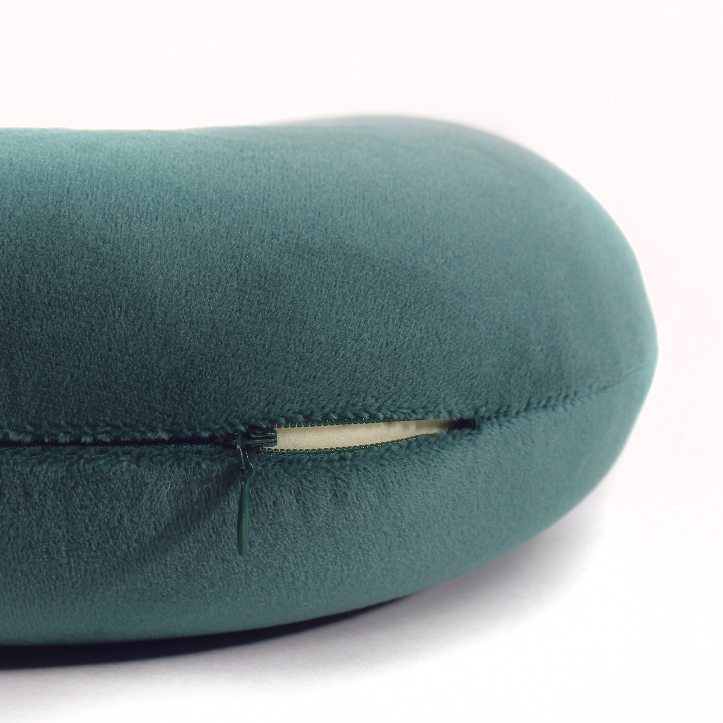 Close up view of the zipper opening on the Memory Foam Travel Neck Pillow in Hunter Green, which is exposing the plush interior inside the pillow's cover.