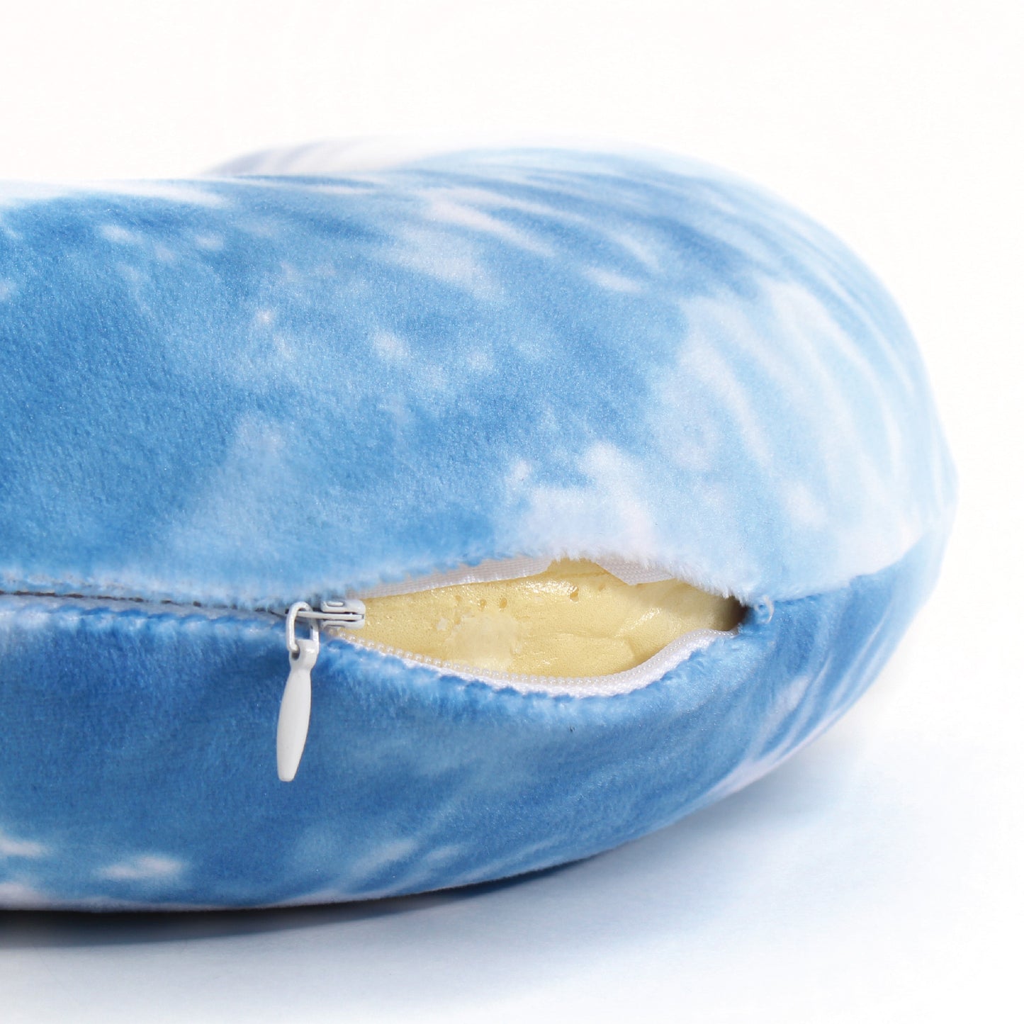 Close up view of the zipper opening on the Memory Foam Travel Neck Pillow in Sky Blue Tie Dye, which is exposing the plush interior inside the pillow's cover.