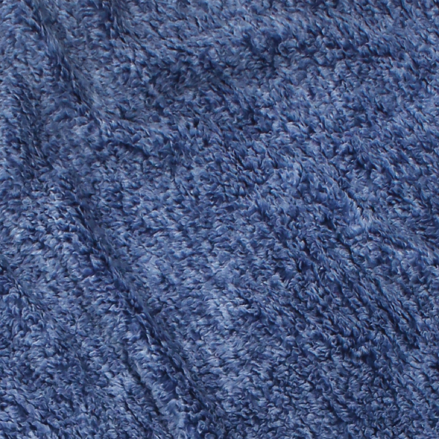 A close-up of the blanket's textured blue fabric that has a soft, fluffy appearance. This machine-washable material exhibits subtle shading variations, adding depth and a cozy, inviting look.