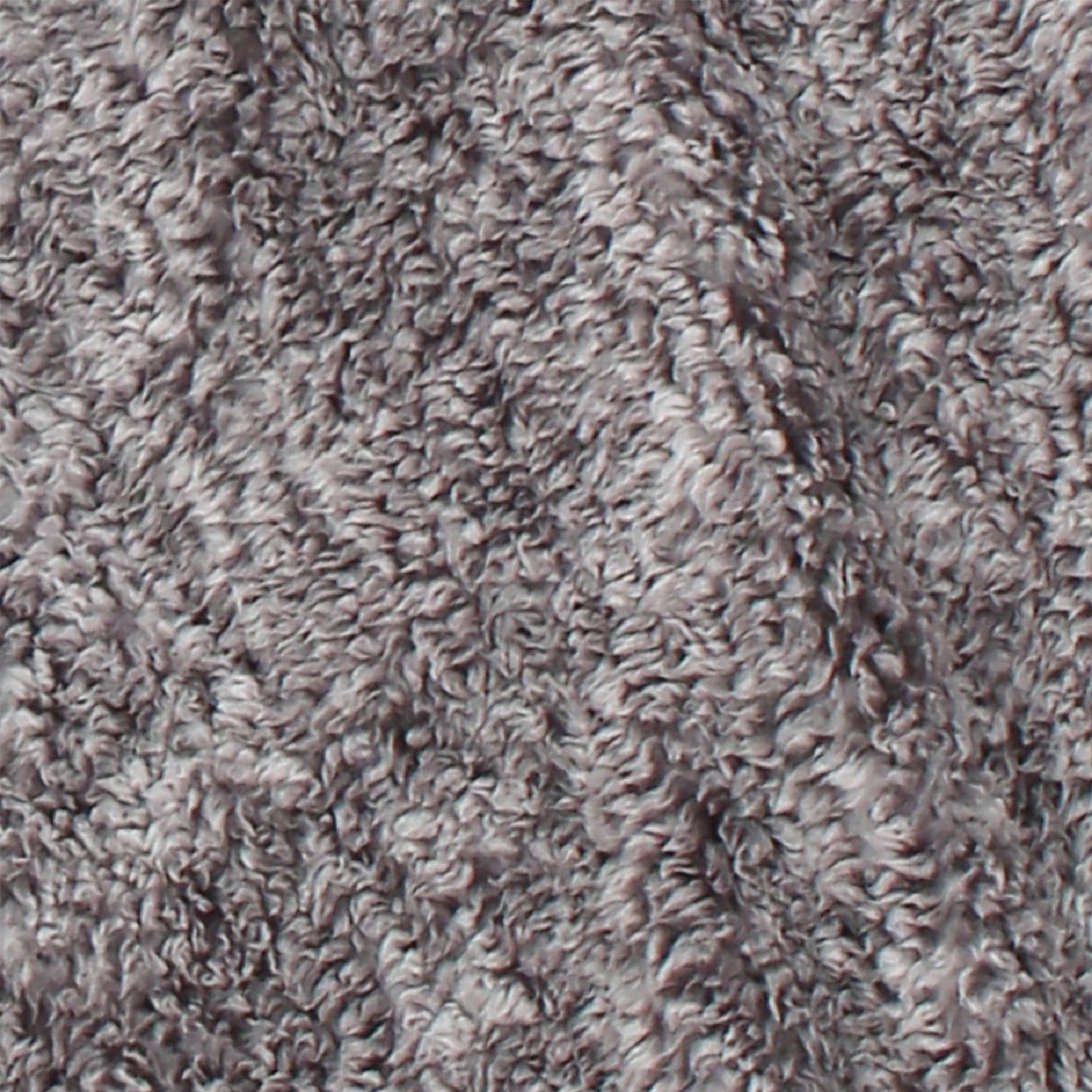 A close-up of the blanket's textured gray fabric that has a soft, fluffy appearance. This machine-washable material exhibits subtle shading variations, adding depth and a cozy, inviting look.