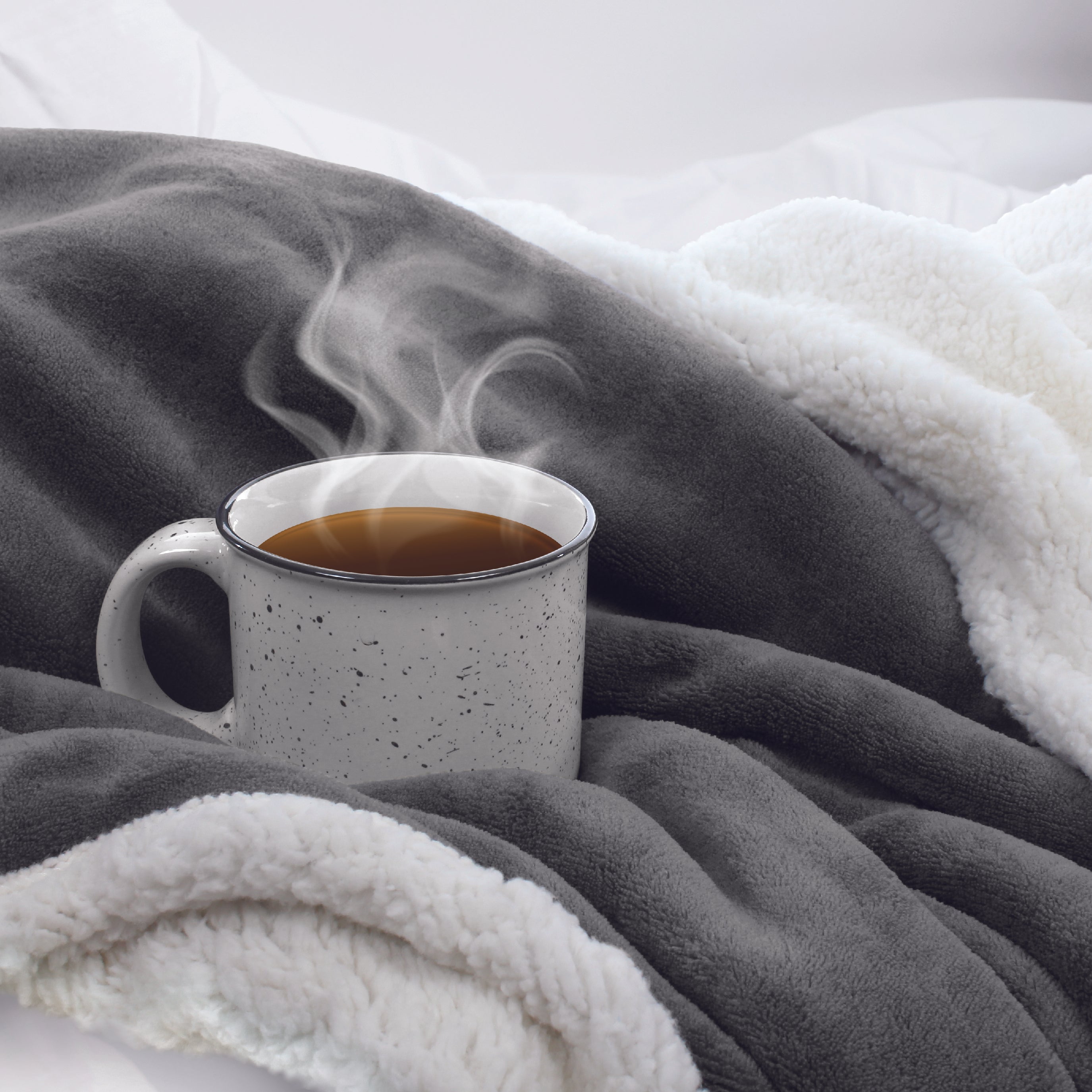 Steaming coffee mug nestled into the Sherpa Fleece Reversible Throw Blanket
