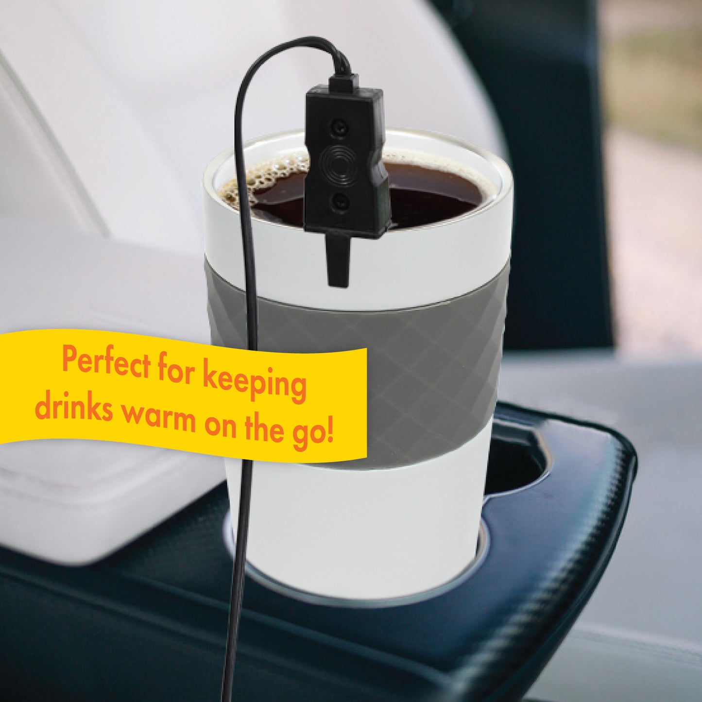 The 12V Beverage Heater sits in a ceramic cup warming coffee, positioned in the cup holder of a vehicle's center console. This accessory is perfect for keeping drinks warm on the go!