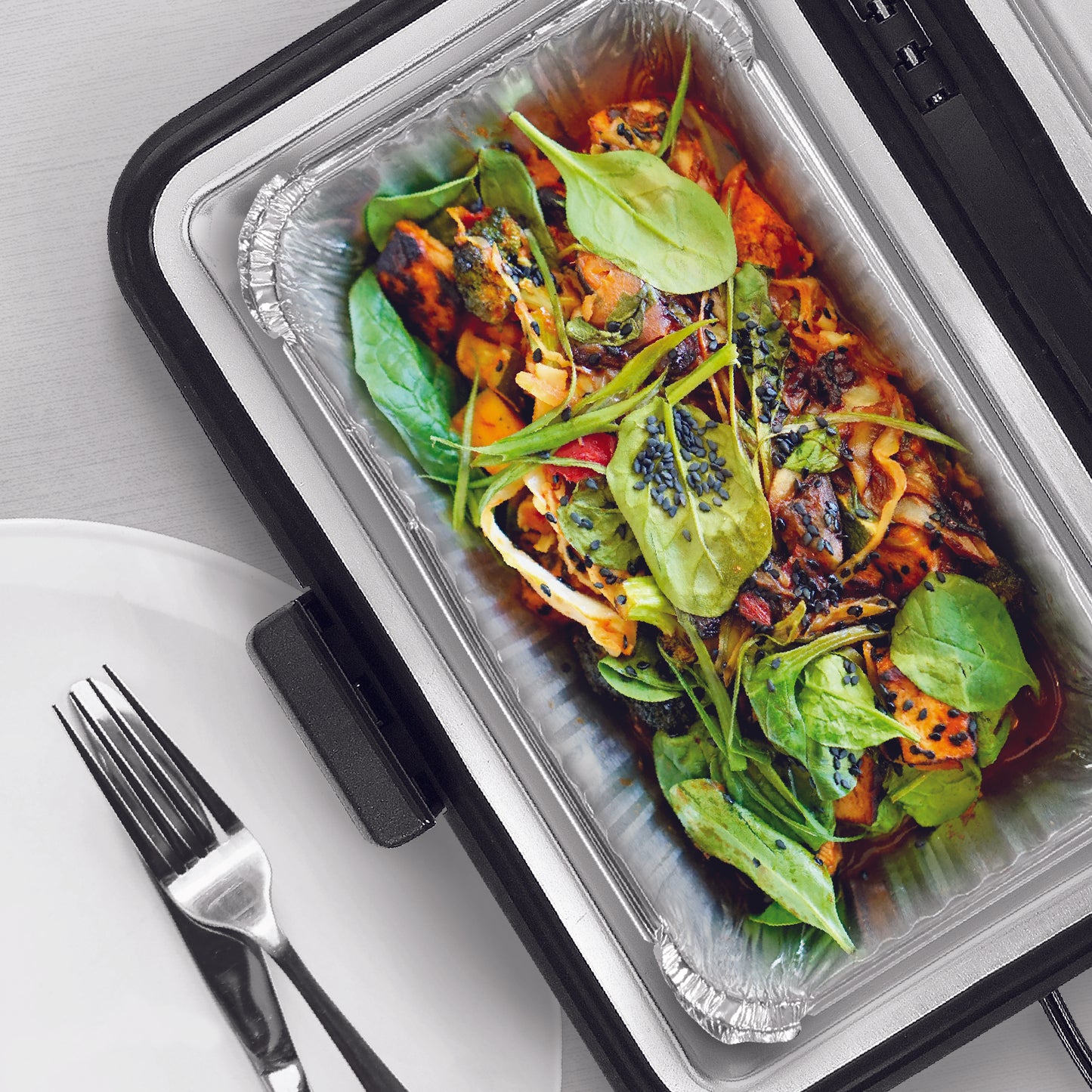 A foil container inserted in the Travel Time Portable Stove filled with warm food.