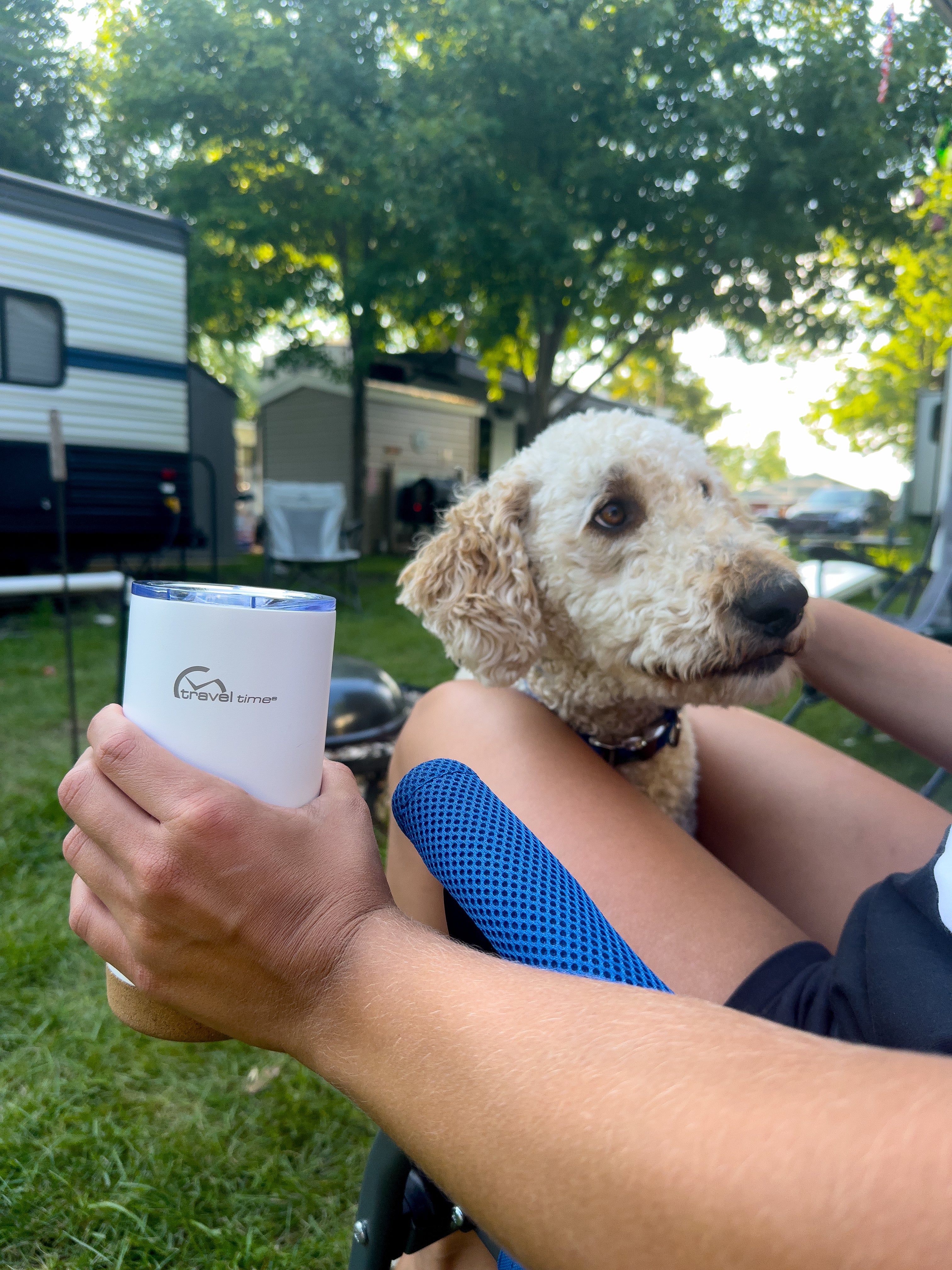 Stainless Steel Travel Tumbler 20oz in white held in the hand of a person hanging out outside their RV camper with their dog