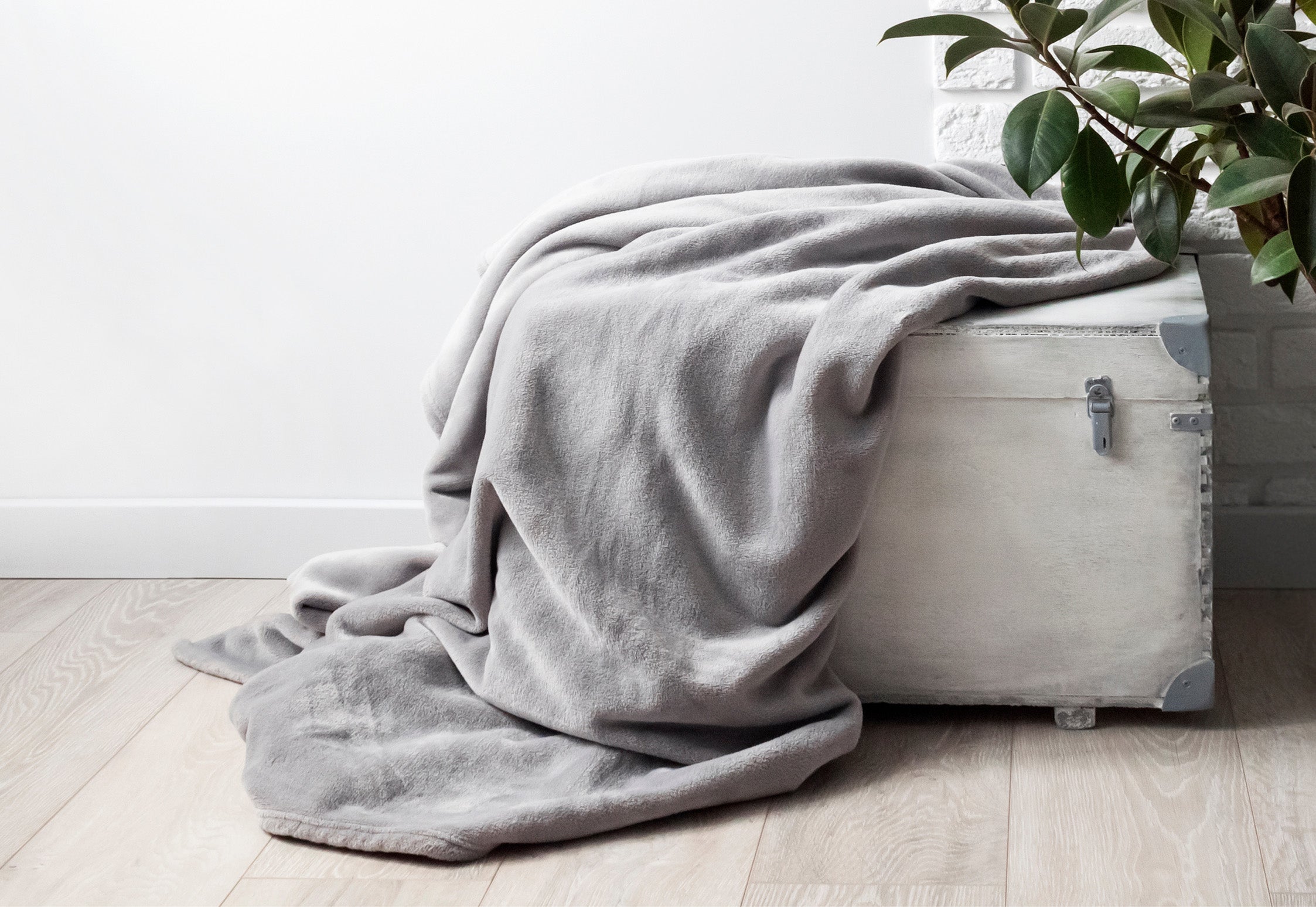 Full/Queen Polar Fleece Blanket draped over a rustic storage chest situated next to some greenery