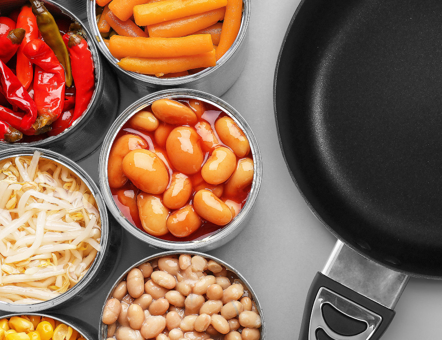 12 Volt Cooking Pan placed next to opened cans of various veggies and foods, including peppers, cabbage, corn, carrots, baked beans, and pinto beans
