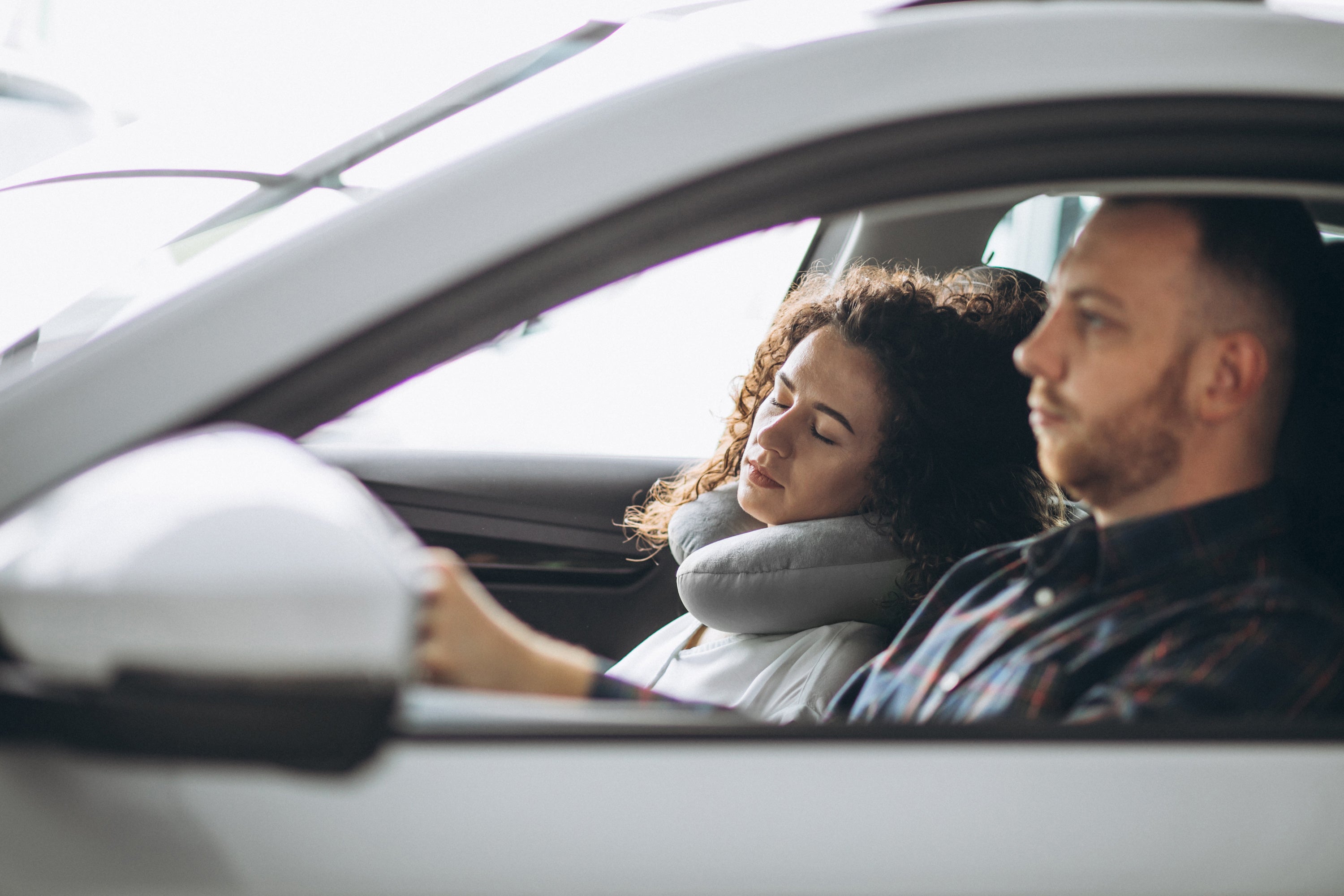 Passenger resting with a Plush Travel Neck Pillow on to support her neck while sleeping during a road trip