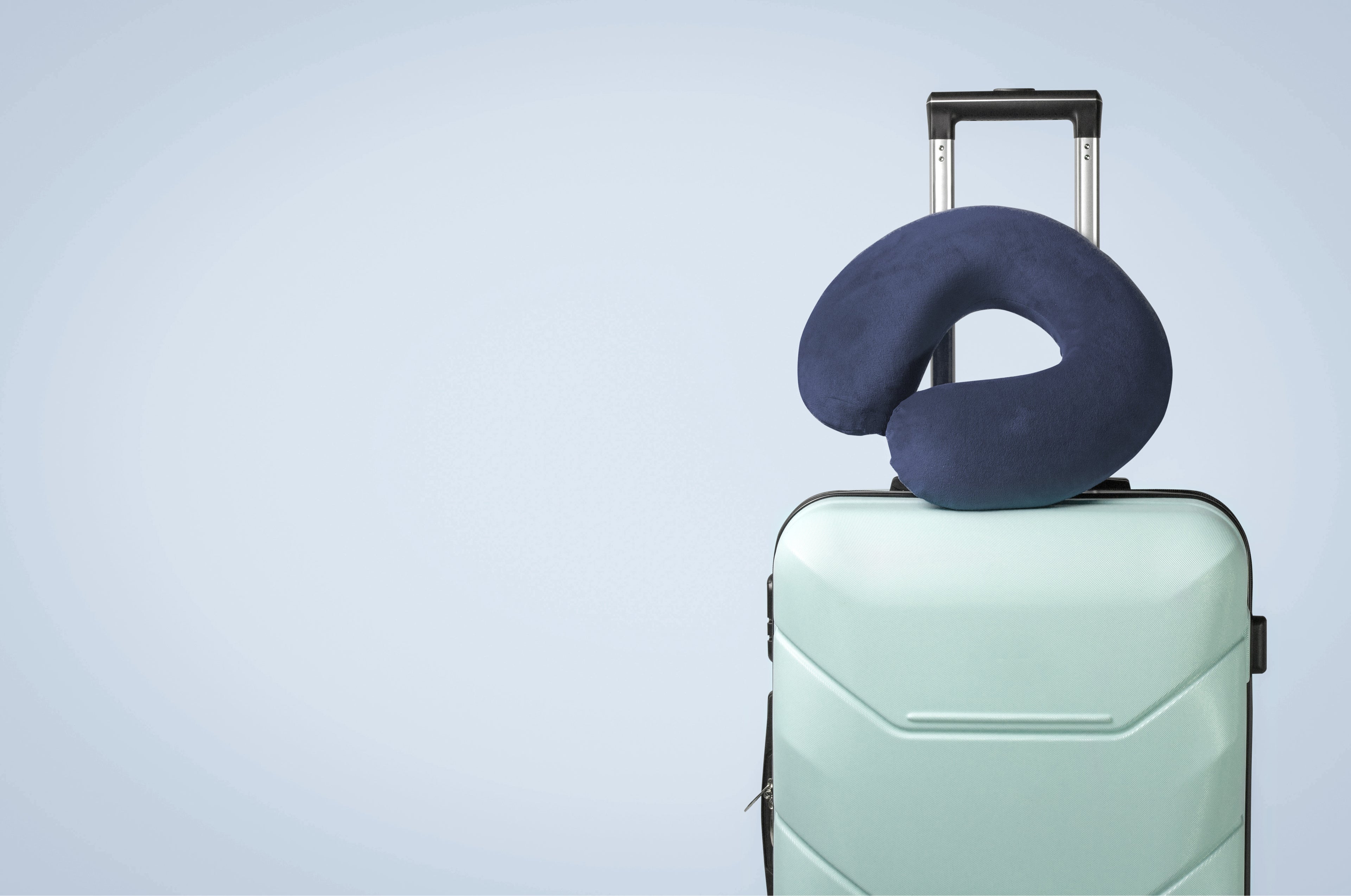 Plush Travel Neck Pillow in Navy sitting atop a piece of luggage in a minimalistic setting