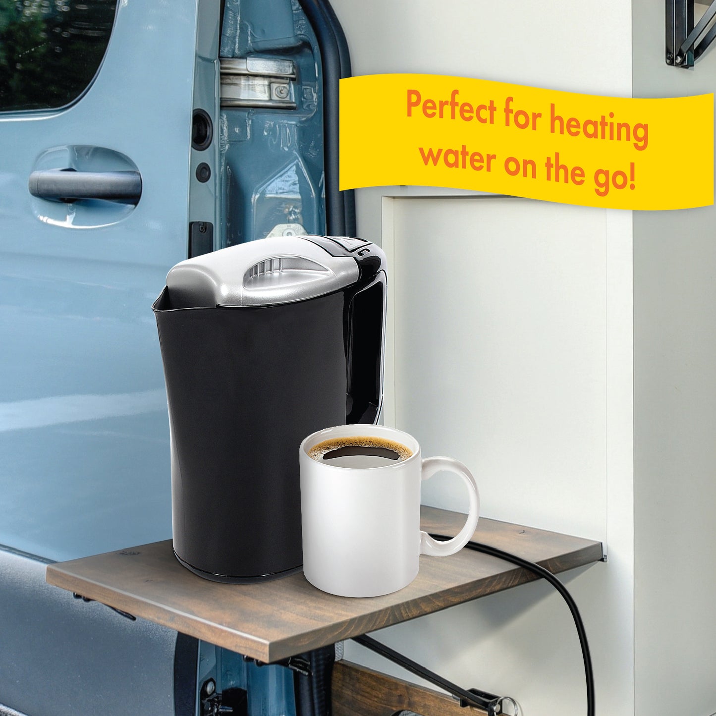 The 12V Smart Pot Kettle with a 12 volt power cord is positioned on a small wooden table that has been folded out of the side of an RV van. A cup of hot coffee sits next to the kettle. The image includes a callout about the kettle being perfect for heating water on the go, which can help with making hot coffee.